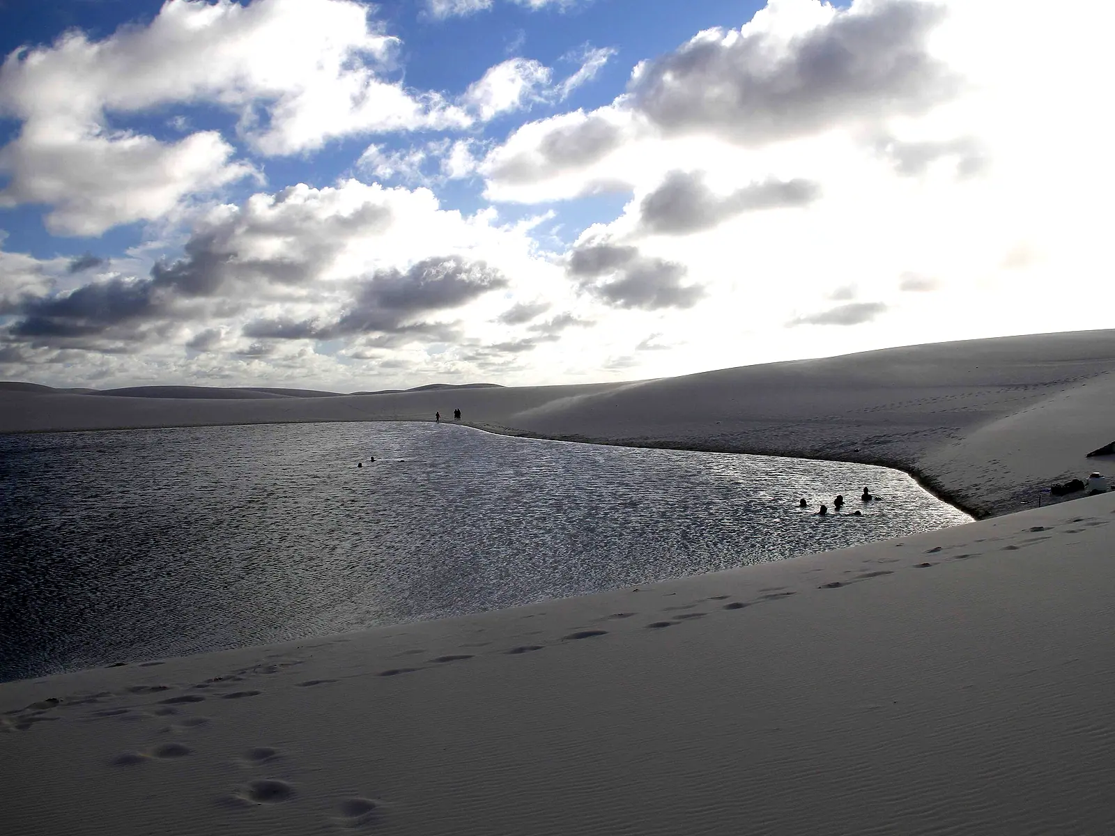 Visitantes caminhando na margem da Lagoa das Andorinhas, entre dunas